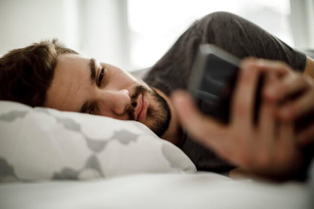 man lying down texting in bed