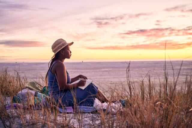 woman reading on beach at sunset