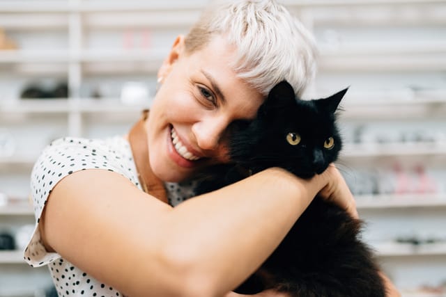 woman smiling and hugging cat