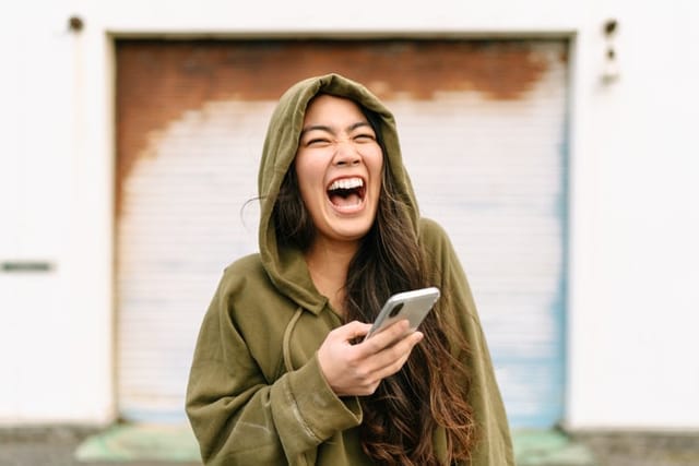 woman laughing while texting