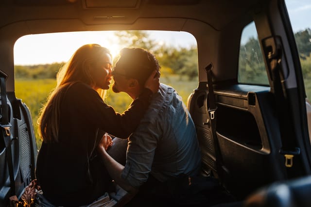 couple kissing in back of car in sunlight