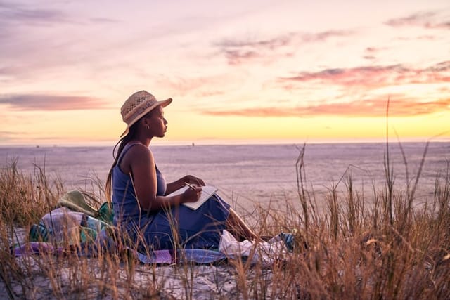 woman journaling on beach at sunset