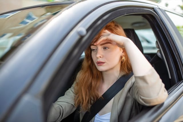 frustrated redhead woman in car