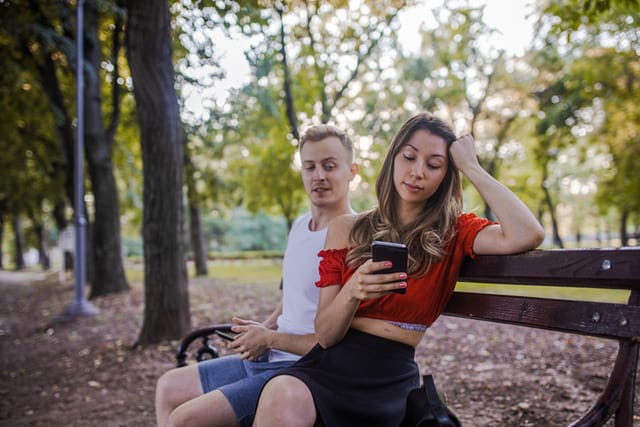 boyfriend reading girlfriend's texts in park
