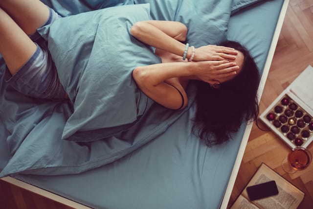 woman covering face in bed