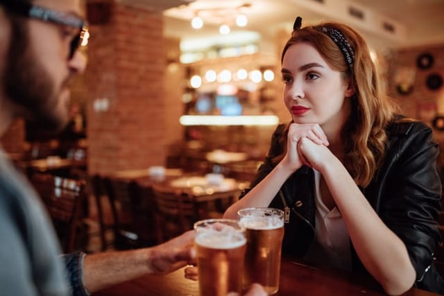 woman skeptically looking at man at pub