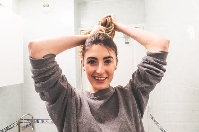 woman putting hair in ponytail
