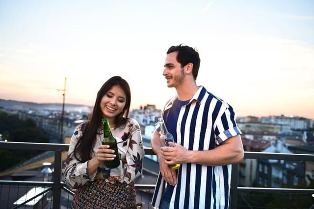 couple flirting at rooftop party with drinks