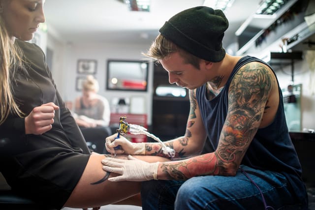 tattoo artist inking up female customer