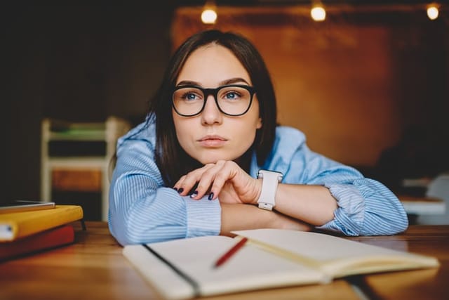 thoughtful woman with glasses and notebook