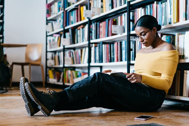 thoughtful young black woman reading at library