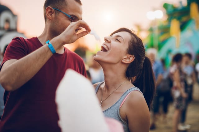 couple enjoying cotton candy at fair
