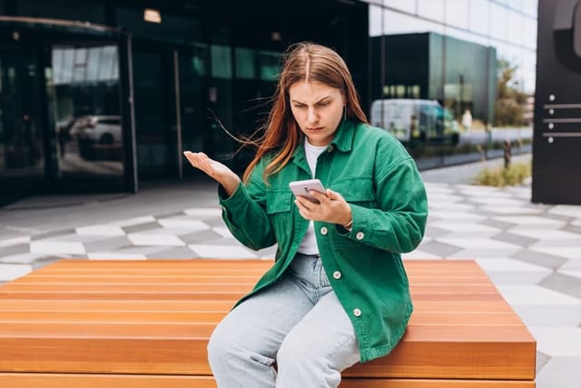 annoyed woman texting on outdoor bench