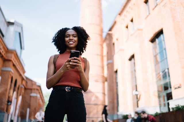 smiling black woman texting on city street