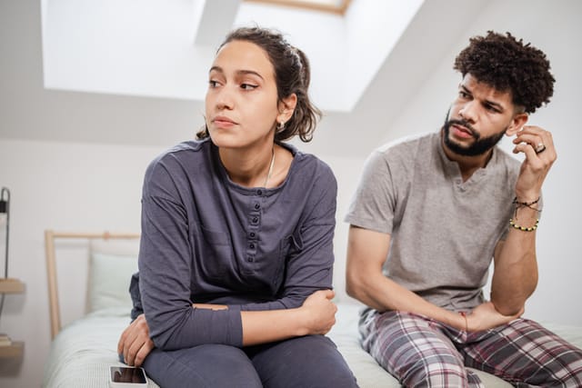 couple sitting on bed after argument