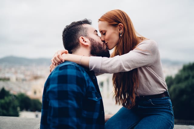 redhead woman and bearded man rooftop kiss