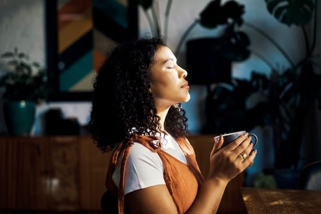 woman meditating closed eyes coffee window