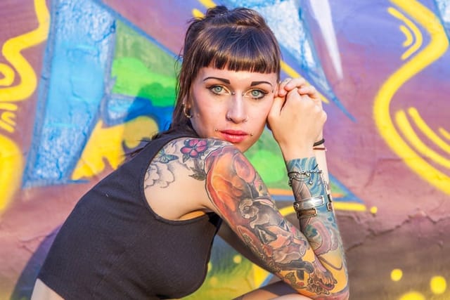 woman with tattoos looking outside