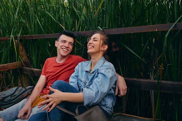 young couple laughing on park bench