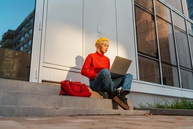 woman using laptop on outdoor steps