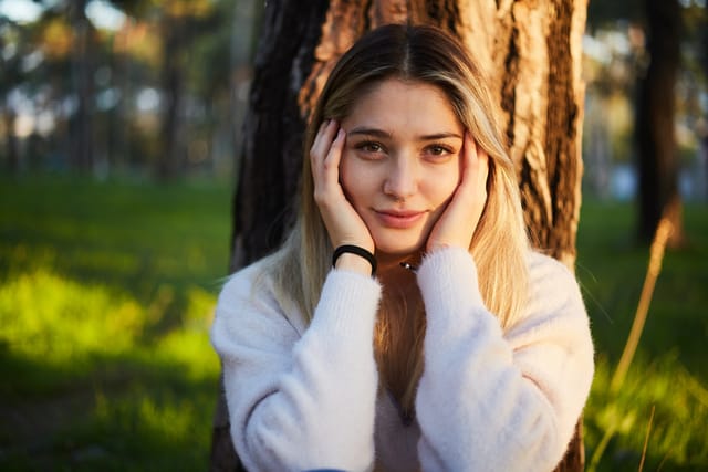 pensive woman sitting under tree in park