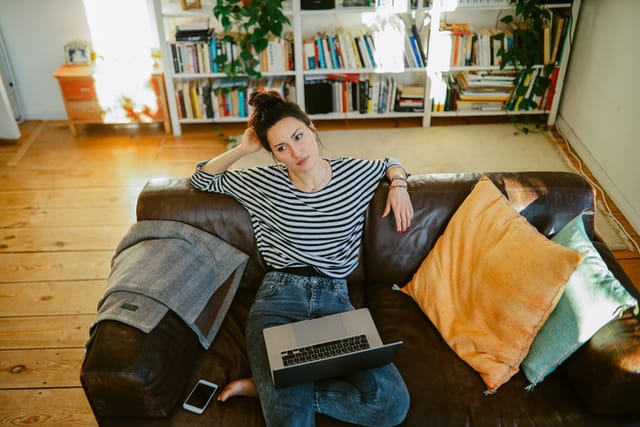 pensive woman on couch with laptop