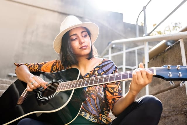 woman playing guitar sitting outside