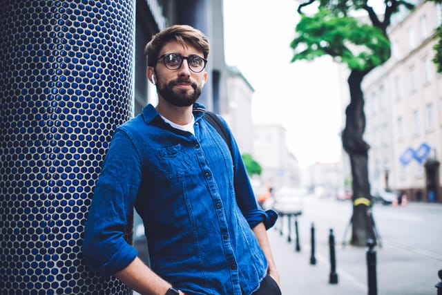 hipster guy with glasses standing outside office