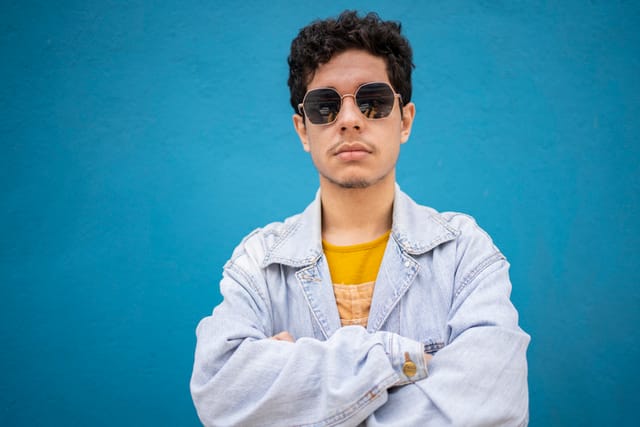 man with arms crossed against wall