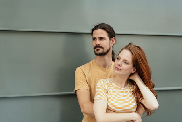 man with arms around redhead girlfriend