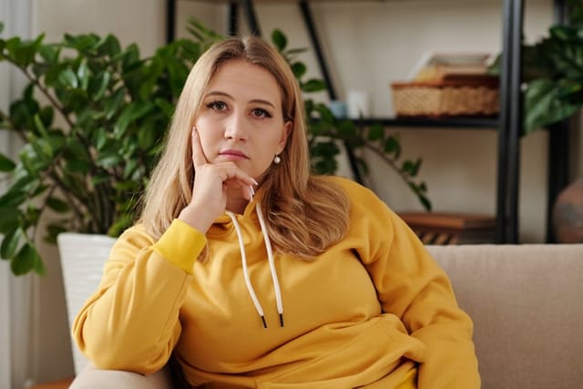 sad girl sitting on couch yellow sweatshirt