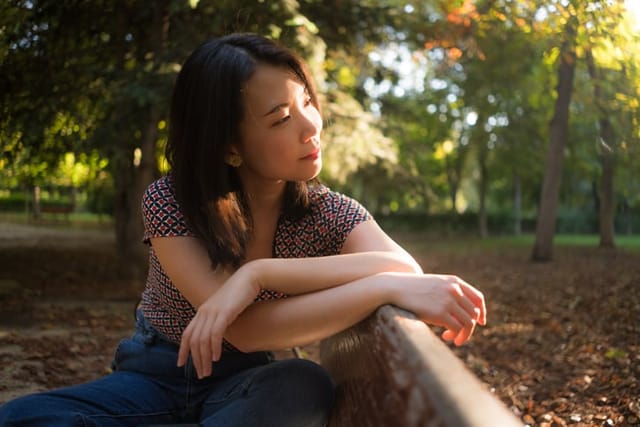 thoughtful woman sitting on park bench