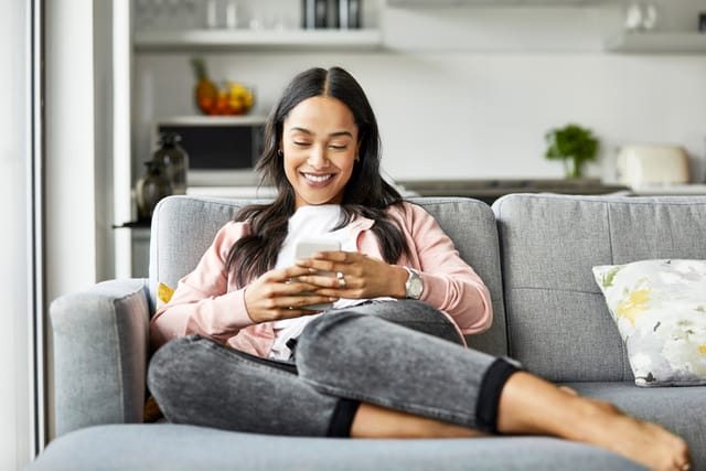 millennial woman texting on couch