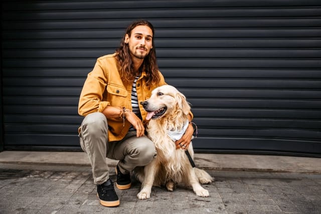 long-haired man kneeling with dog