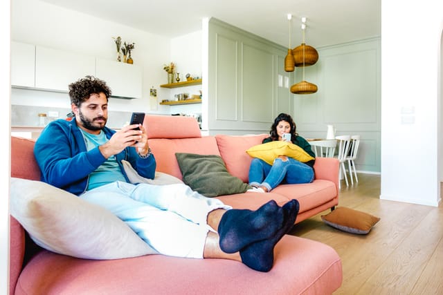 couple ignoring each other on phones in living room
