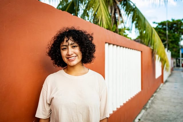 smiling woman standing by palm trees