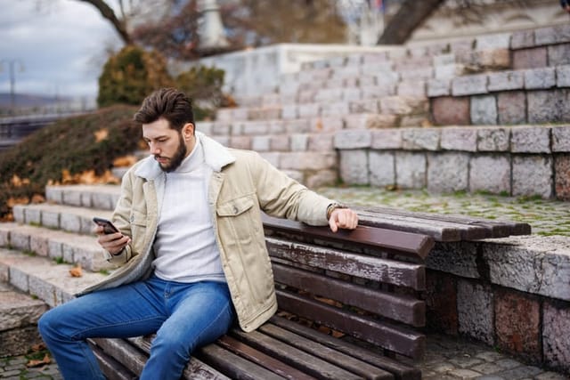 man texting on bench