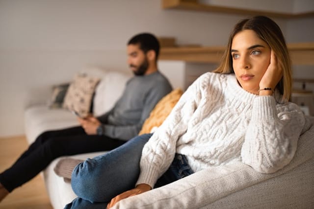 couple sitting unhappily on the couch