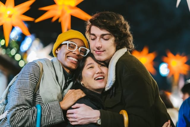 A group of multi-ethnic friends are happily hugging each others at street market at night.