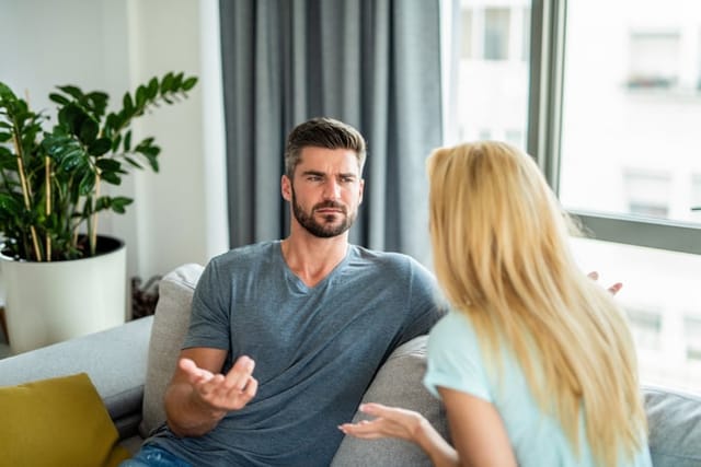 confused boyfriend talking to girlfriend on couch
