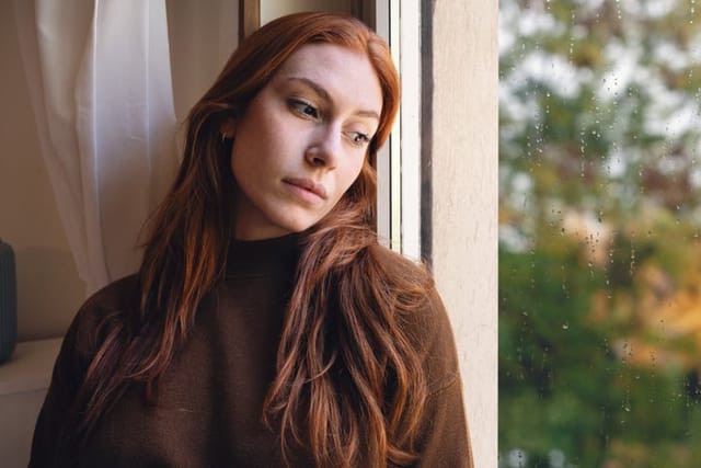 lonely redhead woman looking out window