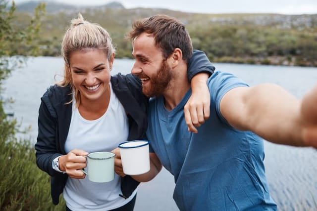 smiling man woman coffee outdoors lake