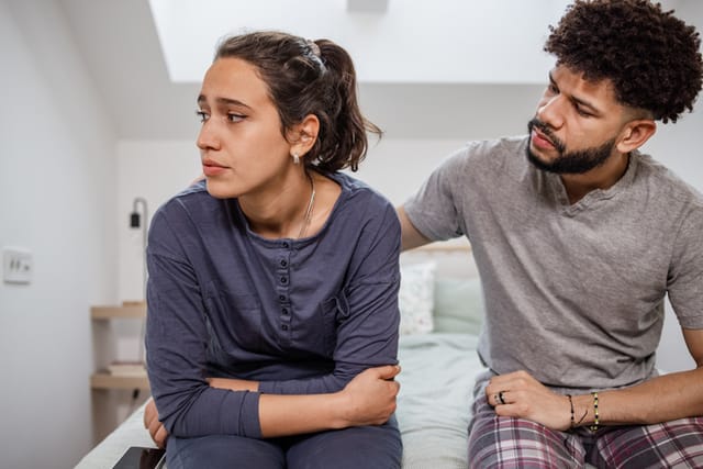 unhappy couple sitting on bed