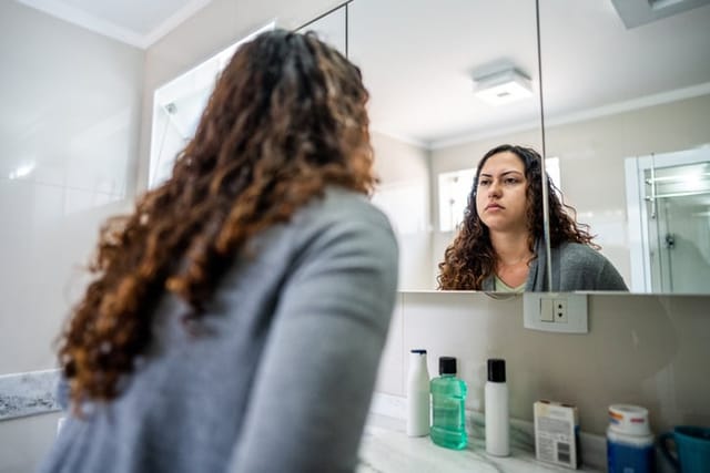 unhappy woman looking in the mirror