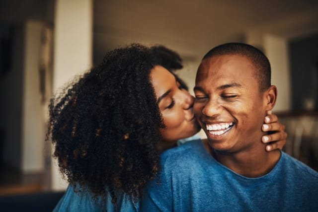 woman kissing boyfriend's cheek laughing