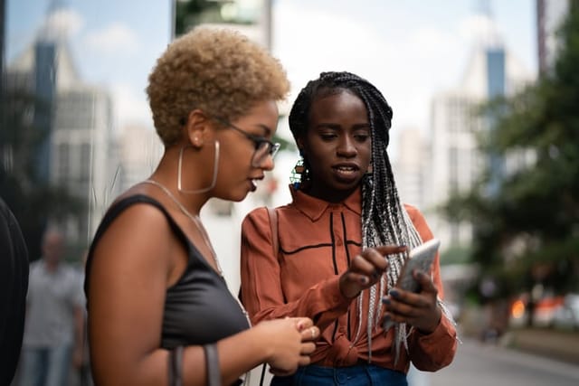 two girls reading text on street
