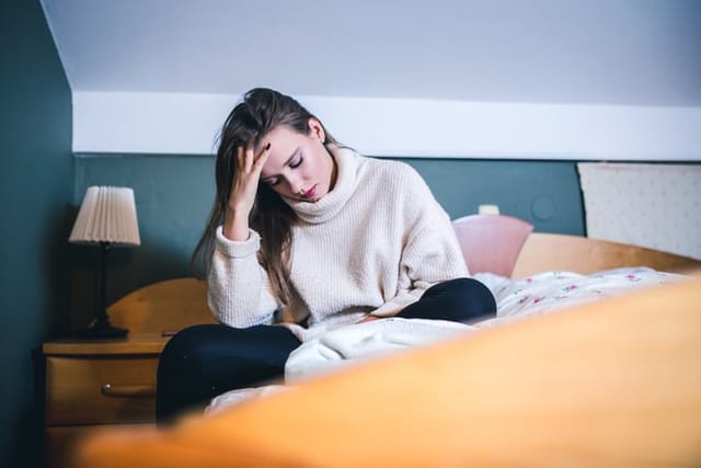 depressed woman sitting on her bed