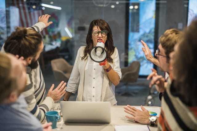 woman using bullhorn during office meaning