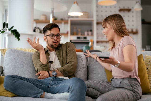 Boyfriend and girlfriend are arguing on the couch. Angry woman is yelling at her boyfriend.