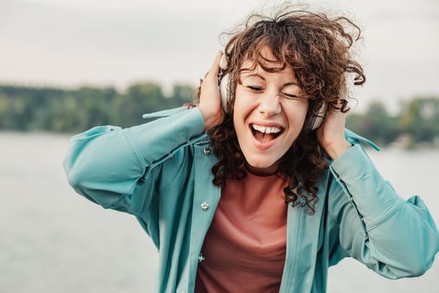 Photo of woman outdoors listening music and smiling